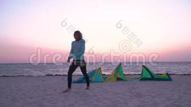 一个穿着潜水服的女人在黎明时分沿着海滩散步，<strong>经过</strong>训练风筝